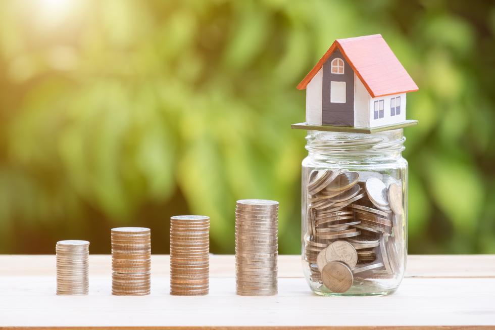 View of Coin Stack with House Model on Green Background, Savings